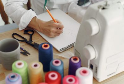 Woman sitting in studio and sew cloth Woman writes the measurements to a notepad. Designes sew cloth. Top view.